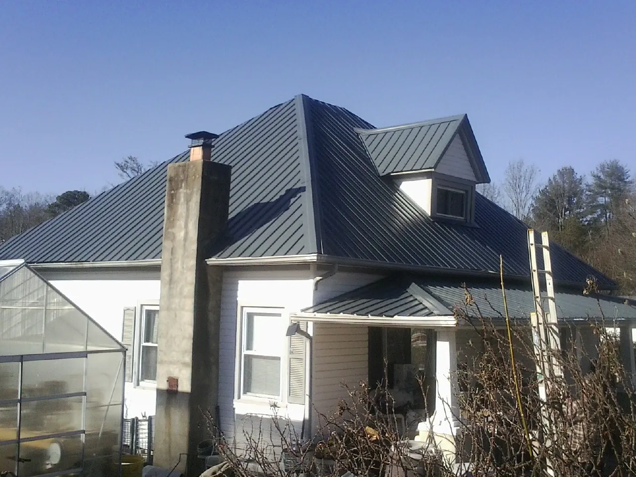 Dark blue standing seam metal roof on a white farmhouse with dormer — Slate & Tile Roof Repair by Roofing Brothers in Frenchglen