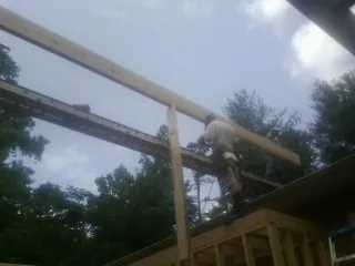 Carpenter setting a ridge beam over a new addition frame — Ice Dam Removal by Roofing Brothers in Frenchglen