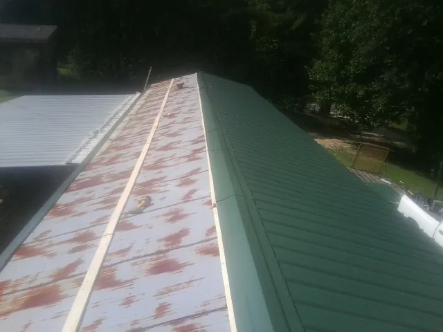 Old rusted panels beside newly installed green metal roofing — Wind Damage Roof Repair by Roofing Brothers in Frenchglen