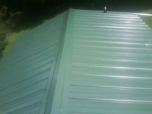 New green metal panels meeting at the ridge of a roof — Flat Roof Repair work by our crew in Frenchglen