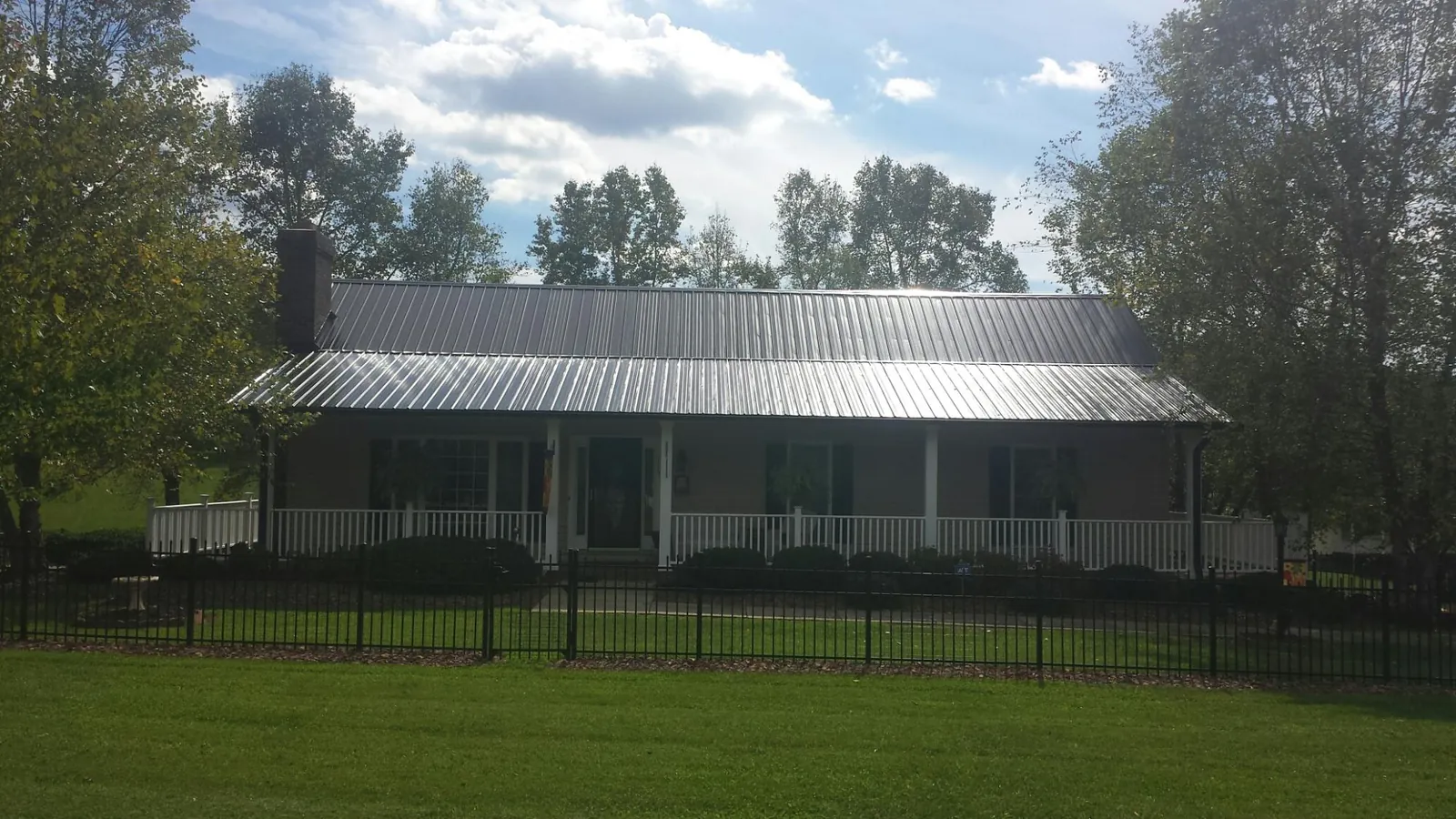 Gray metal roof on a brick ranch with a full width front porch — Gutter Guard Installation work by our crew in Frenchglen