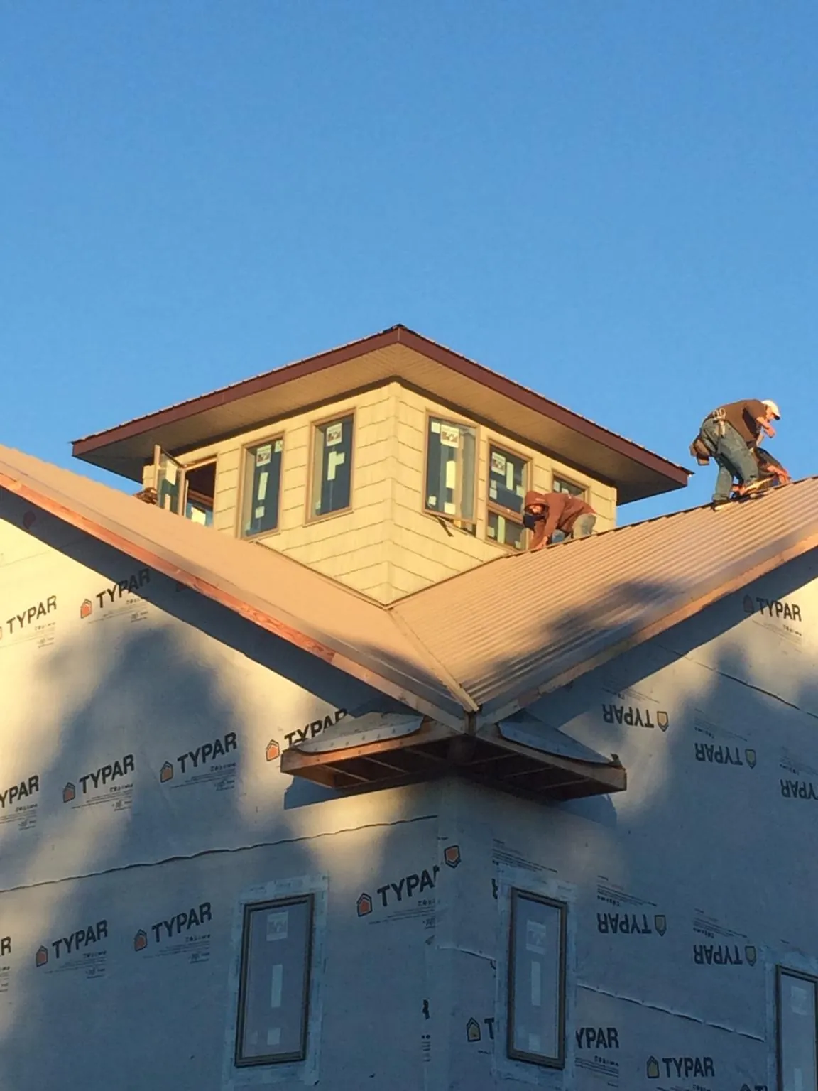 Roofers working around a rooftop cupola on a new metal roof at sunset — Roof Waterproofing in Frenchglen by Roofing Brothers
